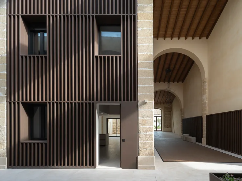 Doorway through a slatted facade adjacent to a vaulted timber ceiling