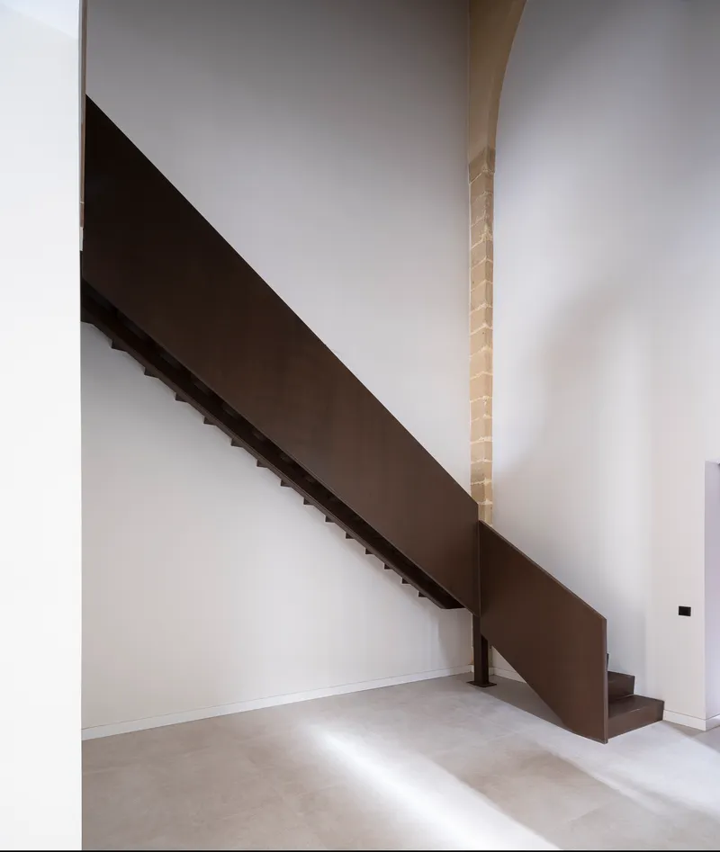 Steel stair against an exposed sandstone column inside a unit