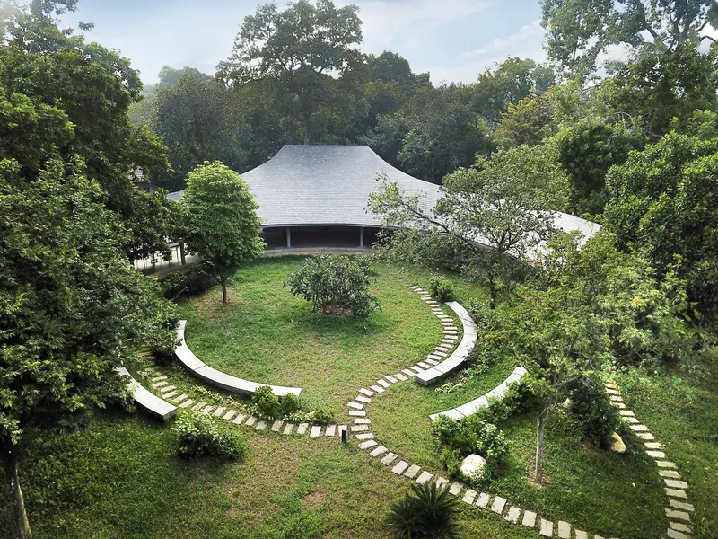 Central courtyard with curved stone pathways radiating across a grass lawn toward pavilions with white tile roofs