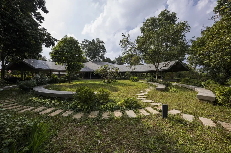 Central courtyard with stepping stone paths radiating through lawn and planted beds between low-roofed wings