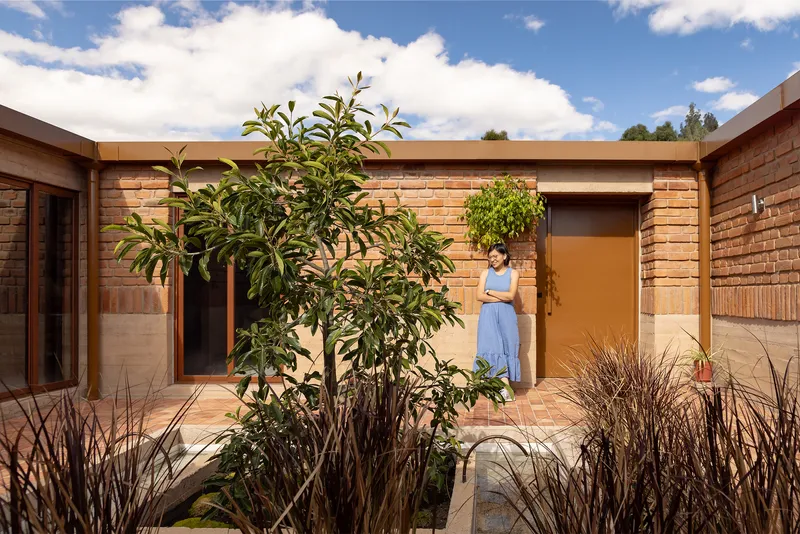Central courtyard with planted beds, timber beams overhead and a figure in a doorway