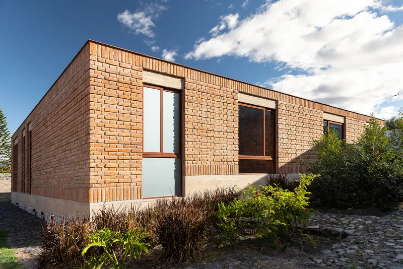 Street facade showing brick walls with varied coursing patterns and recessed timber window frames