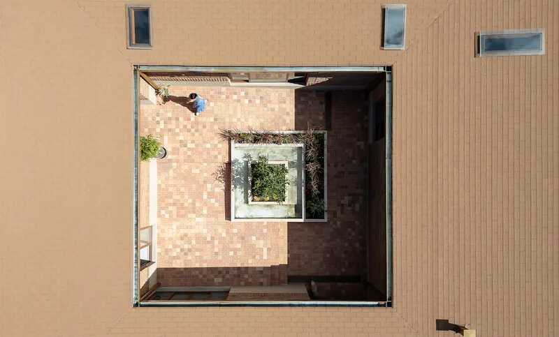 Overhead view of an internal courtyard with checkered brick paving and a central planted bed
