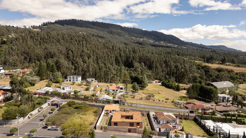 Aerial view of the brick residence within a valley neighborhood below forested mountains