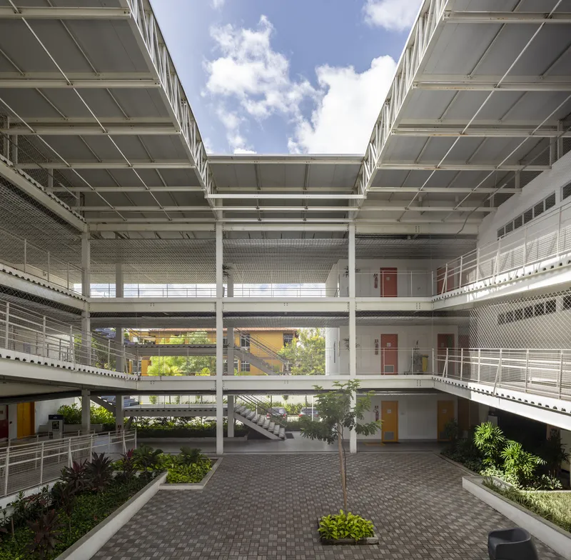 Interior courtyard with three levels of walkways and metal mesh railings under an open sky