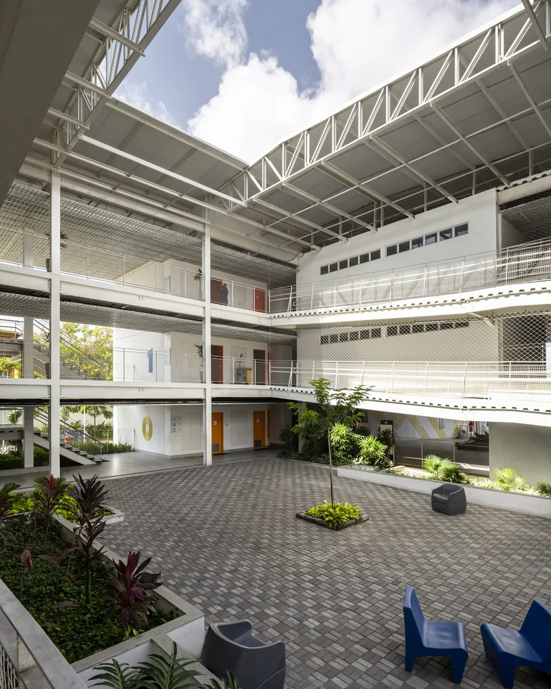 Central courtyard with brick paving, planted beds, and steel walkways under an open lattice canopy