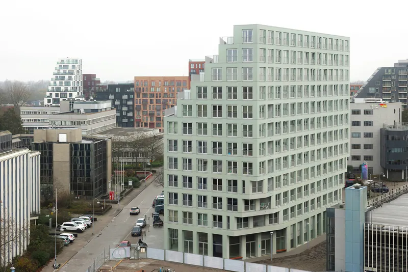 Elevated view of the pale green facade with regular window grid overlooking surrounding urban blocks