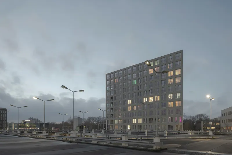 Tower viewed from the highway median at dusk with illuminated windows and streetlights