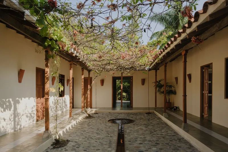 Central courtyard with terrazzo floor, timber columns, and overhead flowering vine trellis