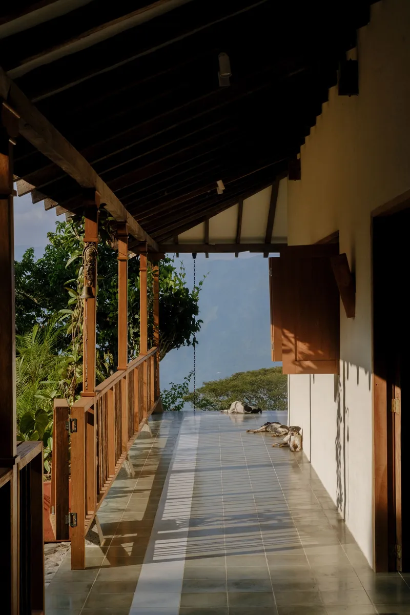Covered walkway with exposed timber rafters, tiled floor, and view to distant water