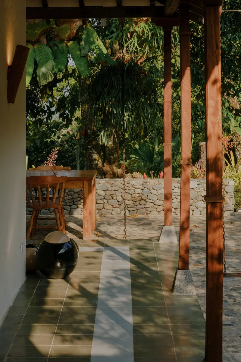 View through timber columns to stone retaining wall and garden in afternoon light