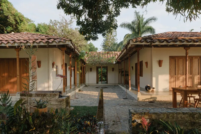 Courtyard with terracotta tile roofs, timber columns, and stone paving surrounded by tropical vegetation