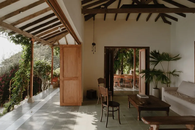 Interior room with exposed timber roof trusses opening to a garden through timber framed doors