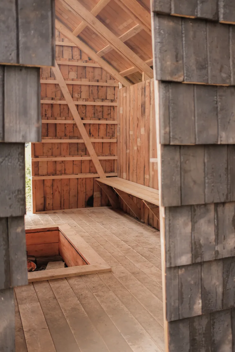 View through doorway showing diagonal timber bracing, built-in bench, and sunken fire pit
