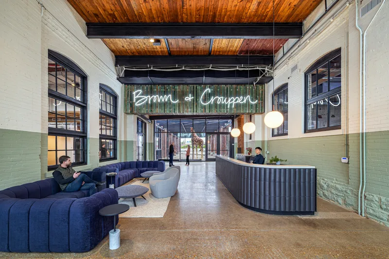 Lobby with curved corrugated reception desk, neon signage, painted brick walls and polished concrete floor