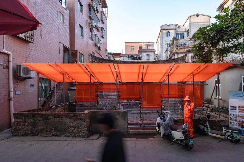 Orange tensile canopy structure with metal frame in a residential courtyard at dusk