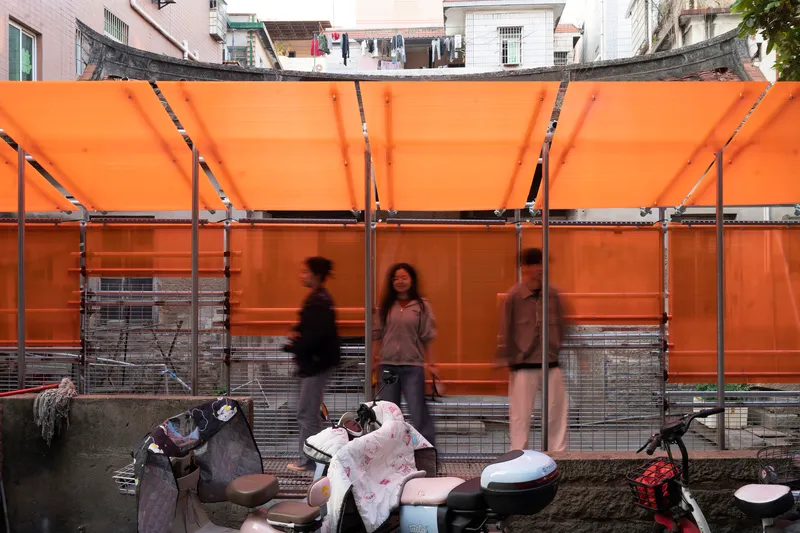 Translucent orange panels and steel frame with pedestrians gathering on scooters below
