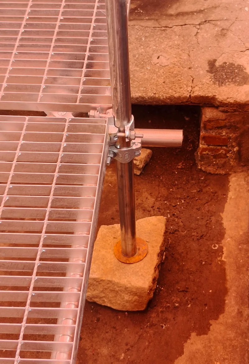 Detail of the steel column base anchored into compacted earth with wire mesh flooring