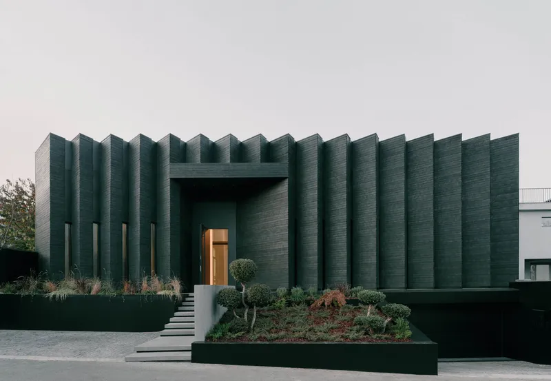 Ribbed facade with vertical fins and recessed entry under overcast sky