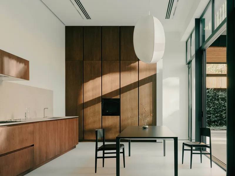 Dining area with timber cabinetry and sunlight streaming through tall glazed doors