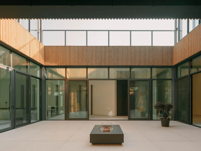 Internal courtyard with corrugated metal cladding and glazed walls surrounding a fire feature