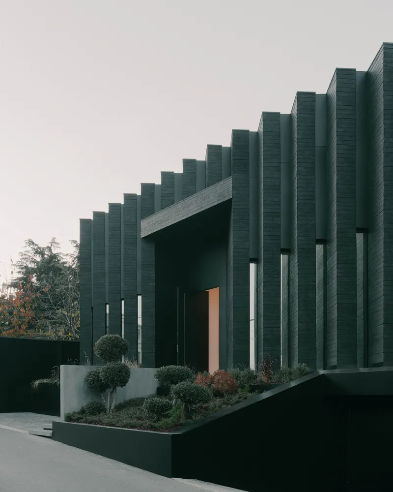 Street view of the vertical fin facade with planted beds at dusk