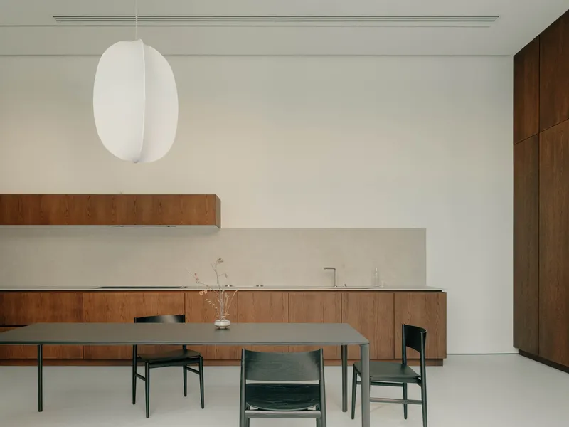 Dining area with walnut cabinetry, grey table and pendant light suspended from white ceiling