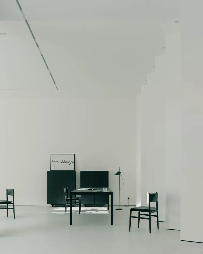 Double-height living space with dark green furniture and artwork on white polished floor