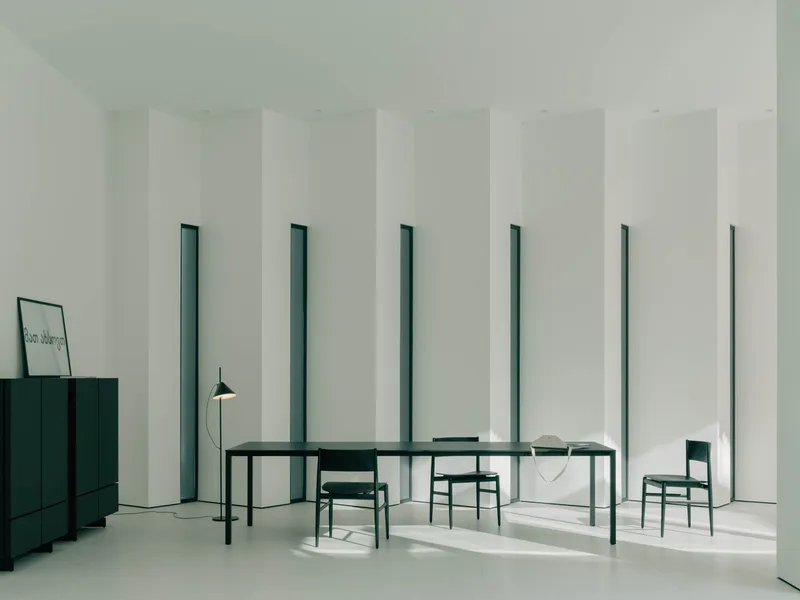Dining room with rhythmic vertical window slots framing dark green table and chairs