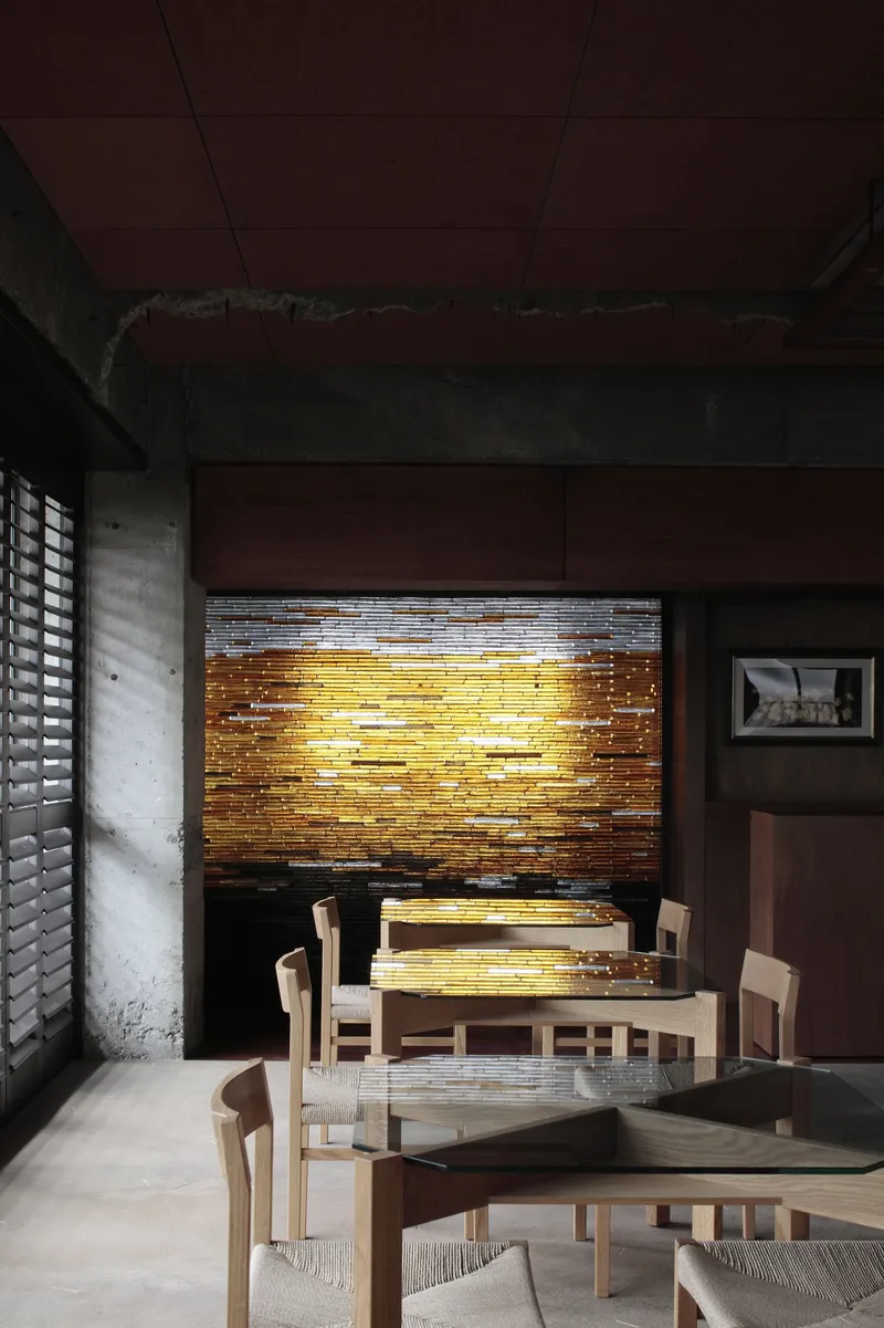 Dining area with backlit horizontal timber screen wall illuminating the seating area at dusk