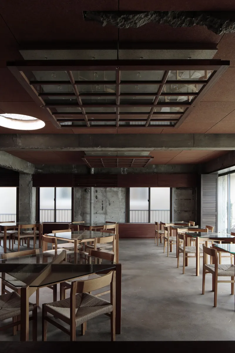 Interior view showing layered timber and concrete ceiling with suspended slatted screens and distant glazing