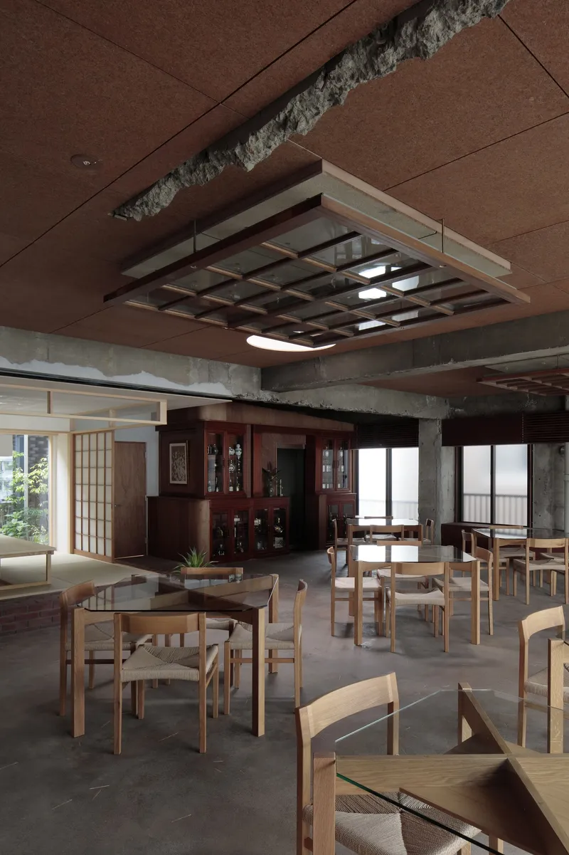 Open dining space with wooden furniture under suspended lattice light fixture and brown paneled ceiling