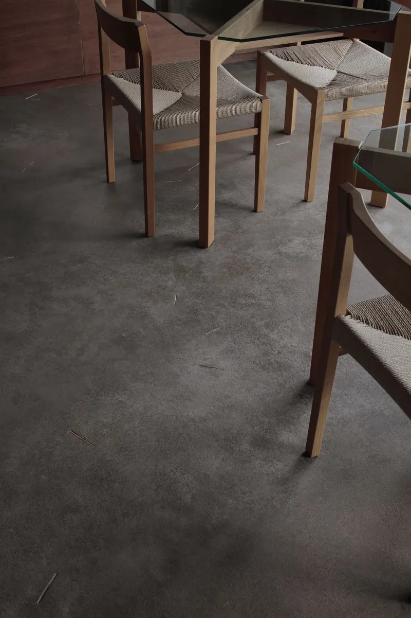 Detail of timber dining chairs with woven seats on polished concrete floor