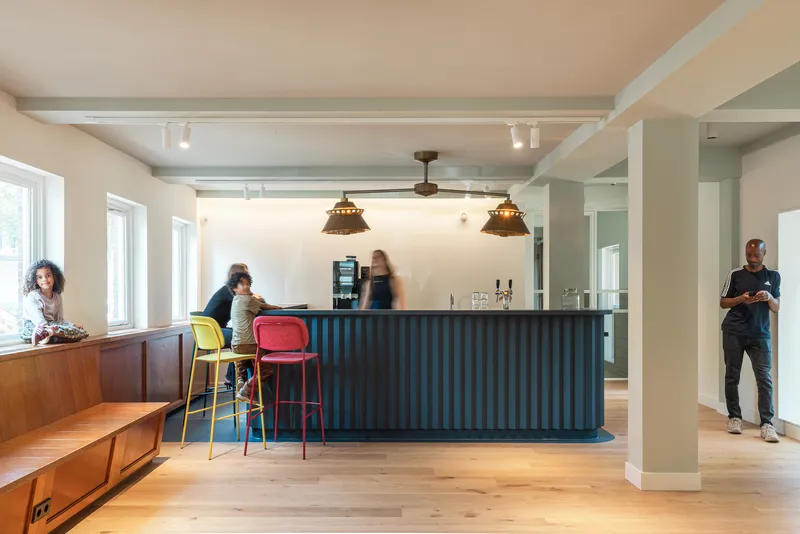 Open kitchen with dark fluted island, pendant lights, and people seated at colorful stools