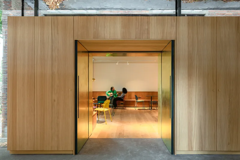 View through timber portal with angled reveal into meeting room with people seated in chairs
