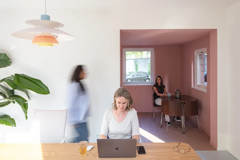 Open-plan living space with pink alcove dining area, pendant light and person in motion blur