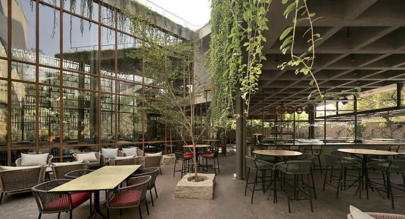 Double-height courtyard with planters and glazed facade beneath an exposed concrete waffle slab