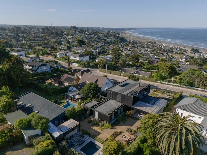 Aerial view of clustered roofs and courtyards in a coastal neighborhood with palm trees