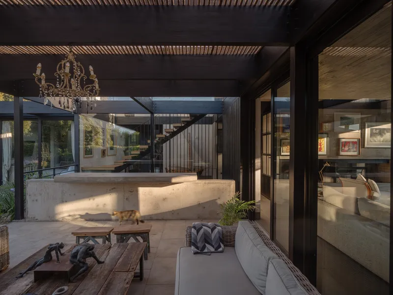 Covered terrace with curved concrete bar and timber-slatted ceiling overlooking an interior courtyard
