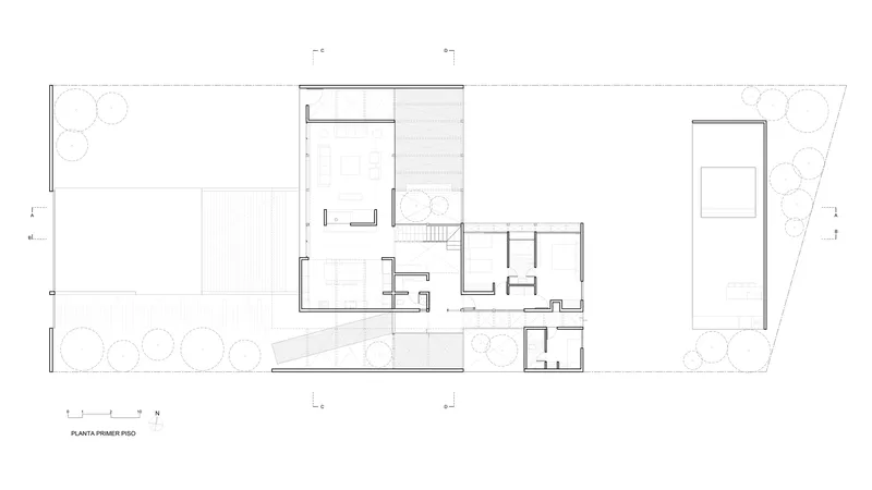 Ground floor plan drawing showing open living spaces flanked by planted courtyards on a sloped site