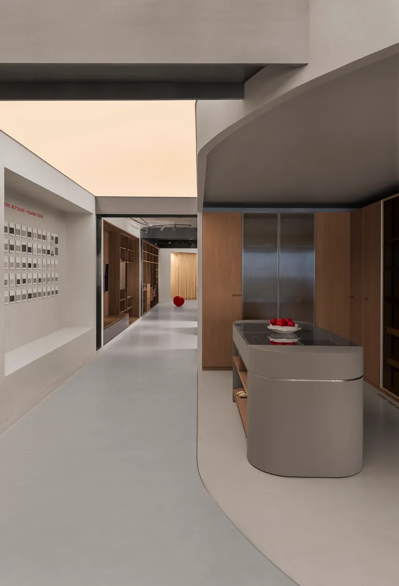 Open interior gallery with grey resin flooring, a curved counter, and a sample wall of material tiles