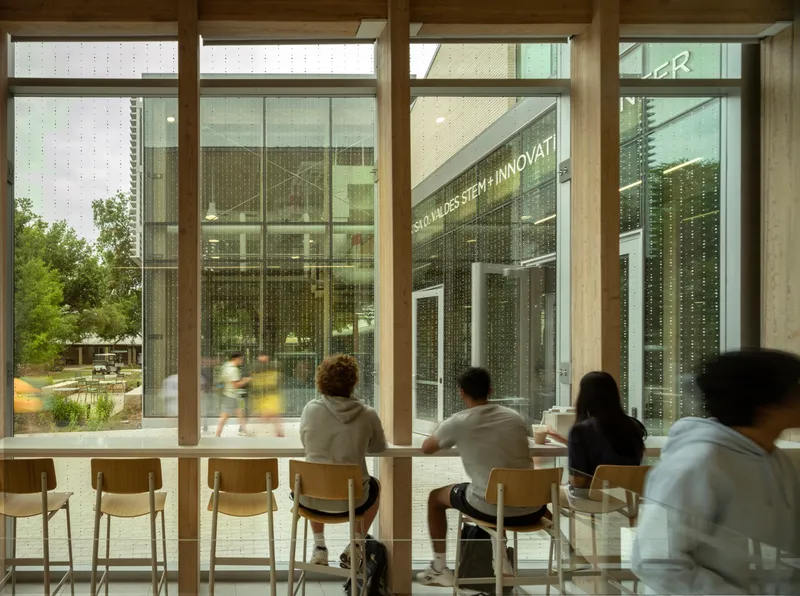 Timber-framed window counter overlooking a planted courtyard with people seated in dappled sunlight