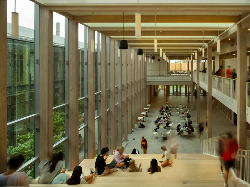 View down into double-height lobby with timber column screens and people seated along balcony edge