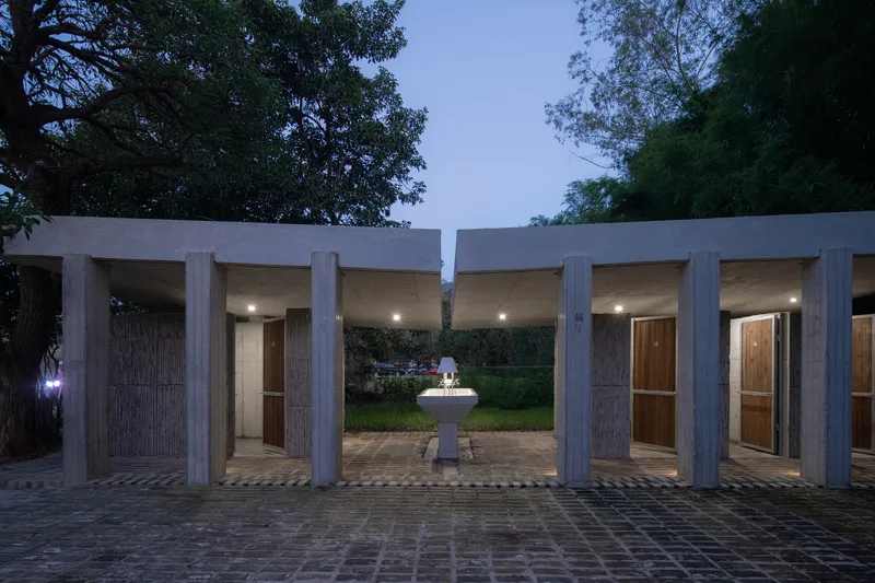 Covered colonnade at twilight with concrete columns framing doorways and a central fountain