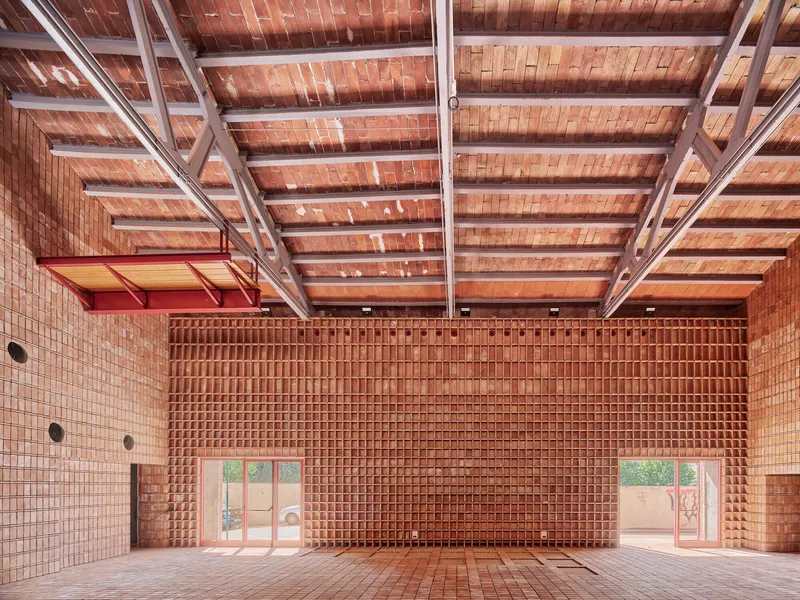 Interior view showing brick walls, exposed steel roof structure, and glazed doors opening to a courtyard