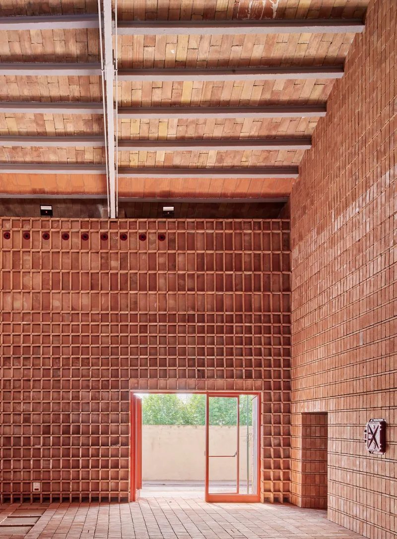 View toward the glass door with open-grid brick wall and timber beam ceiling in soft afternoon light
