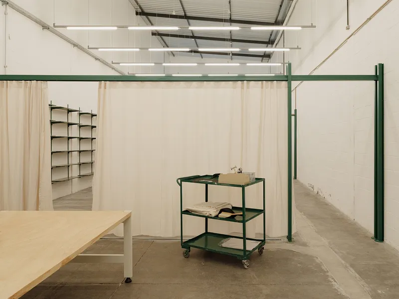 Green steel framing system with fabric panels dividing the workspace and a three-tier rolling cart