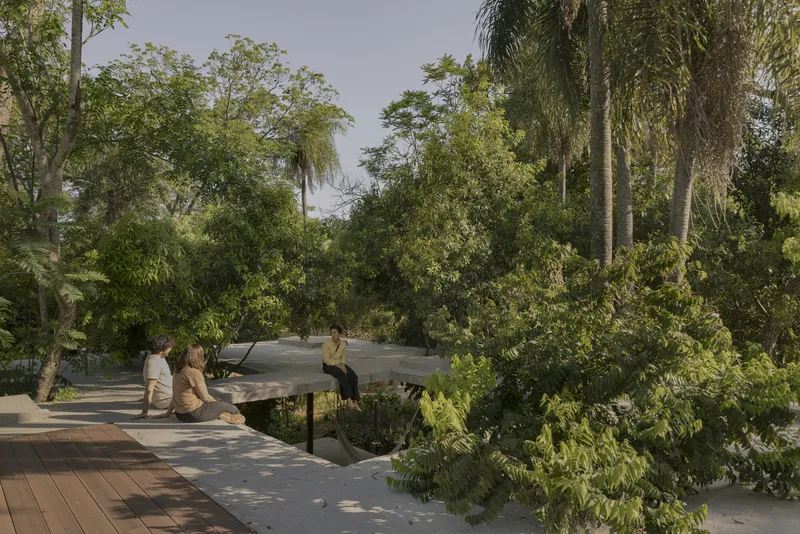 Concrete roof canopy floating above people seated on a terrace surrounded by lush garden plantings