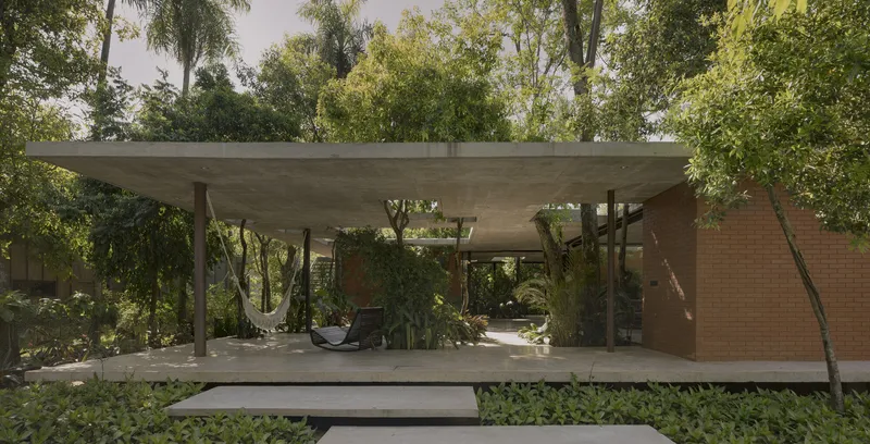 Long view of the elevated concrete roof supported by slender columns within the forested site