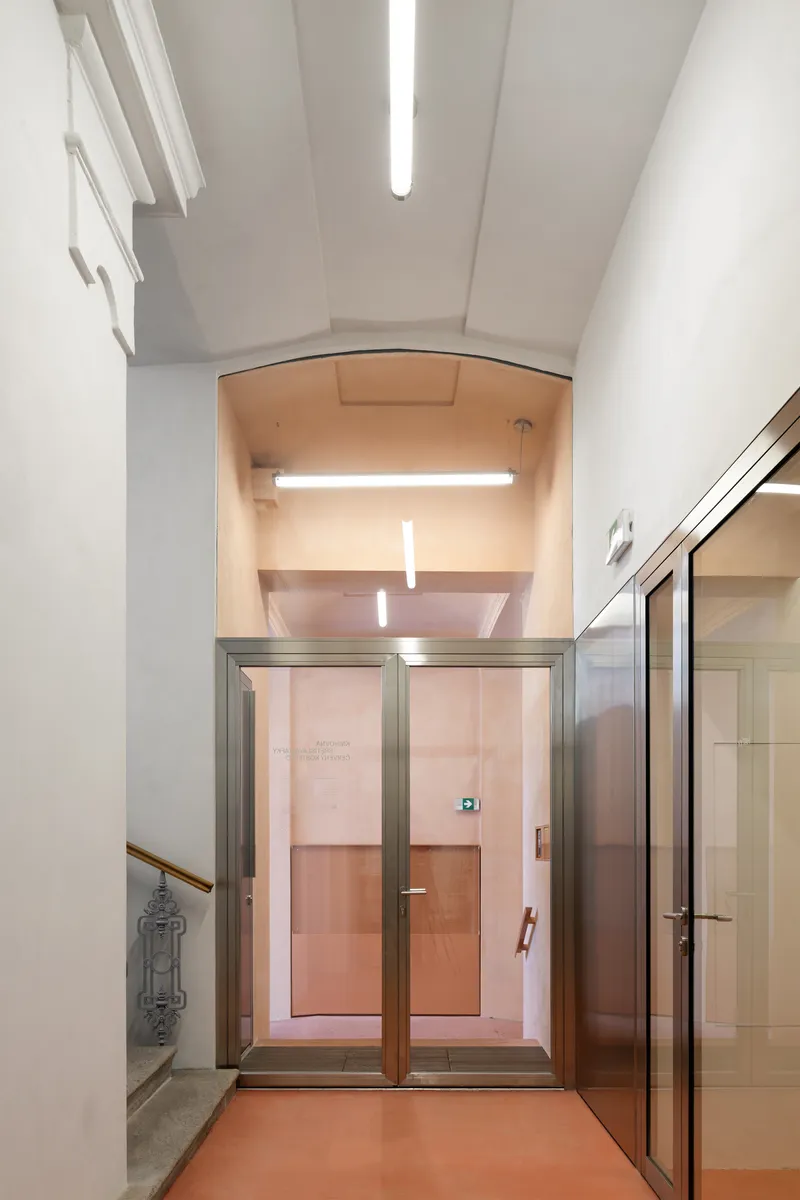 Entrance vestibule with arched opening framing a stainless steel elevator and warm terracotta flooring